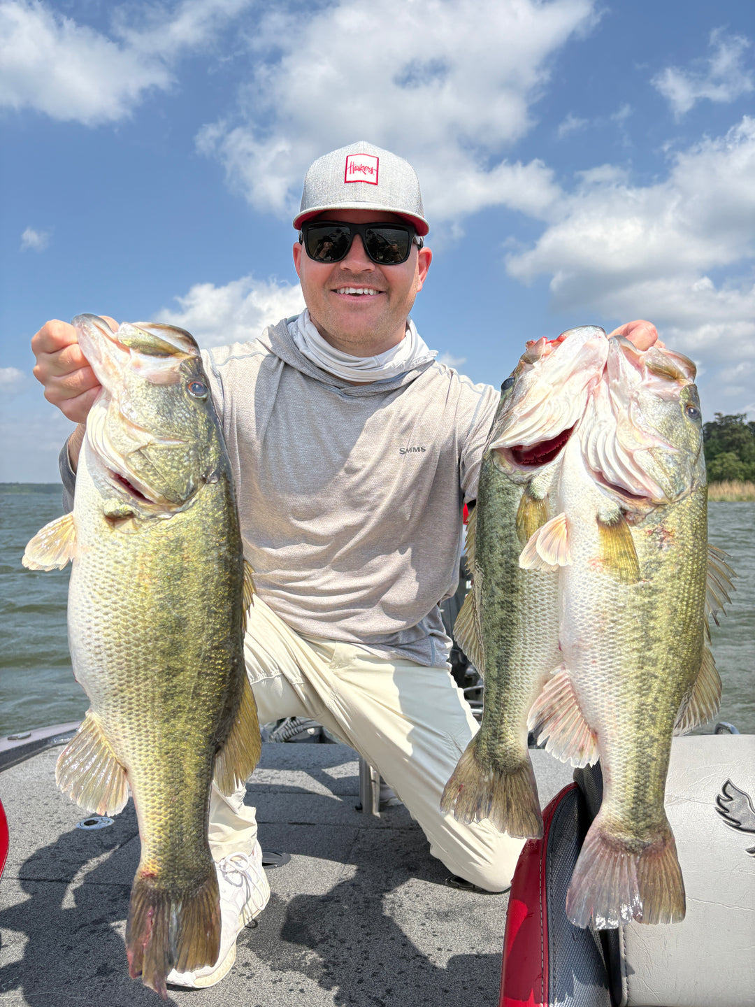 Bass fisherman holding up 3 good largemouth bass on the back of a boat.