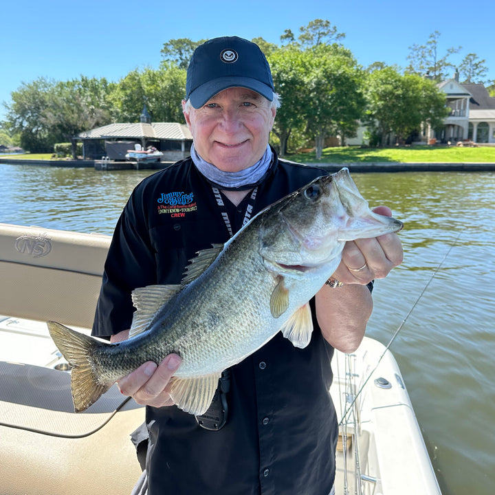 A manholding up a largemouth bass in front of a dock on Lake Conroe. 